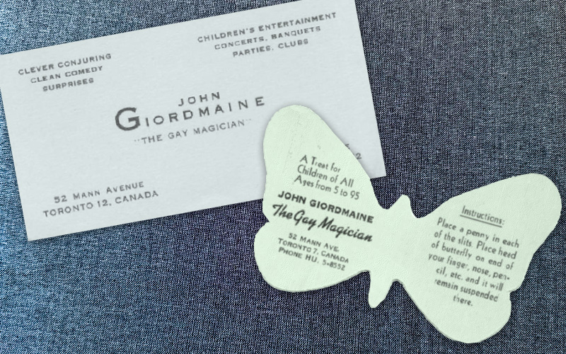 A business card and a promotional paper butterfly giveaway from magician John Giordmaine with the branding "The Gay Magician"